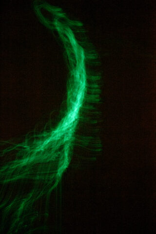 Vor einem dunklen Hintergrund erscheint eine hellgrüne Wellenlinie mit Leuchteffekt.