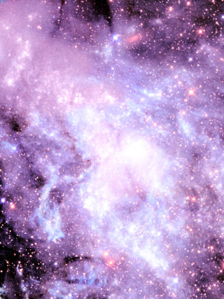 Ein lebendiges Bild eines Nebels mit dichten Wolken aus Gas und Staub, der in Blau- und Lilatönen leuchtet und über den zahlreiche helle Sterne verstreut sind.