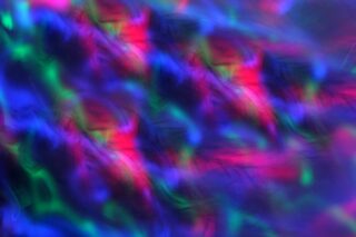 Mehrfarbiges abstraktes Bild mit verschwommenen Mustern aus rotem, grünem und blauem Licht, die ineinander übergehen und einen lebendigen Weichzeichnereffekt erzeugen.