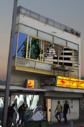 Ein zweistöckiges Gebäude mit einem ungewöhnlichen, abgewinkelten Obergeschoss, großen Fenstern, Straßenkunst, einem leuchtenden Schild mit einem Gesicht und Menschen, die in der Abenddämmerung darunter spazieren gehen.