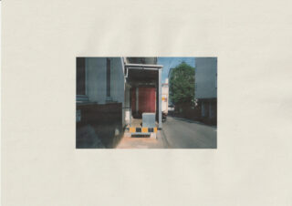 Ein LKW fährt rückwärts an eine Laderampe neben einem Gebäude in einer ruhigen Straße, im Hintergrund ist ein Baum zu sehen.