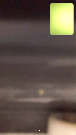 Ein verschwommenes Bild mit dunklen horizontalen Bändern und einem hellgrünen Quadrat in der oberen rechten Ecke.