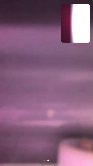 Ein verschwommenes Bild mit violetten Farbtönen und einem kleinen Einschub, der in der oberen rechten Ecke eine leuchtend weiße vertikale Form auf rotem Hintergrund zeigt.
