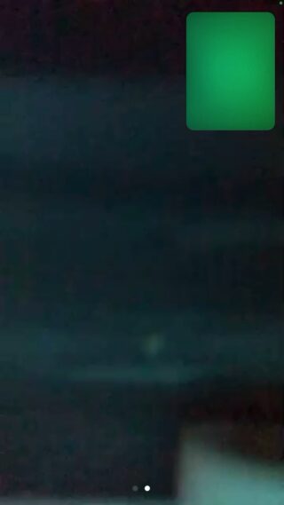 Unscharfes, dunkles Bild mit einem kleinen, hellgrünen Quadrat in der oberen rechten Ecke; unten in der Mitte sind zwei weiße Punkte sichtbar.