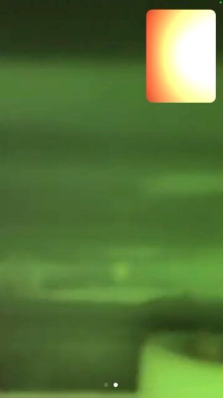 Ein verschwommenes, grün getöntes Bild mit einem leuchtend gelben und orangefarbenen Farbverlaufsrechteck in der oberen rechten Ecke.