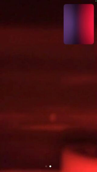 Ein verschwommenes Bild in Rot und Dunkeltönen mit einem kleinen Farbverlaufsrechteck in der oberen rechten Ecke, das einer Videoanrufschnittstelle ähnelt.