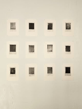 Zwölf quadratische abstrakte Drucke sind in einem 3x4-Raster auf einer hellen Wand angeordnet und jeweils auf weißem Papier montiert.