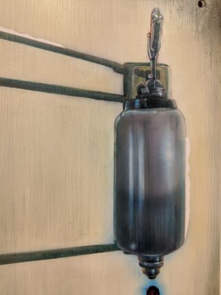 Eine Nahaufnahme eines an einer Wand montierten metallischen zylindrischen Objekts mit daran befestigten Rohren, möglicherweise Teil einer industriellen oder mechanischen Anlage.