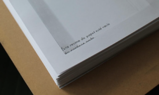 Eine Nahaufnahme eines Stapels weißen Druckerpapiers auf einer braunen Oberfläche, mit teilweise sichtbarem spanischen Text auf dem obersten Blatt.