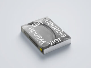 Auf einer hellen Oberfläche liegt ein Buch mit dem Titel „Die vier eigenen Wände“, mit einem Coverbild in Graustufen und fettem weißen Text auf der Vorderseite.