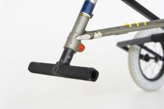 Nahaufnahme des Vorderrahmens eines Fahrrads mit einer schwarzen Fußraste, einem Teil des Lenkervorbaus und einem Teil des Vorderrads mit einem weißen Reifen.