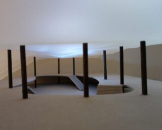 Eine Nahaufnahme eines Architekturmodells mit einer kreisförmigen Struktur, die von dünnen vertikalen Säulen getragen wird und im Inneren mehrere Ebenen aufweist.