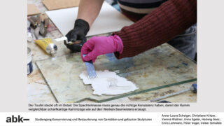 Eine Person mit rosa Handschuhen glättet mit einem Spachtel weißen Kitt auf einer Oberfläche und erzeugt so strukturierte Linien, während eine andere Hand ein kammähnliches Werkzeug über die Fläche hält.