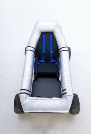 Eine Art Kettcar ohne Lenker, der äußere Rahmen ist eingewickelt mit Folie.