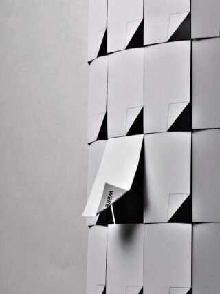 Eine Säule aus weißen Papierkarten, von denen eine teilweise angehoben ist, sodass das darunter aufgedruckte Wort „WHERE“ sichtbar ist.