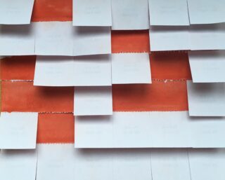 Reihen weißer rechteckiger Papiere sind versetzt auf einem orangefarbenen Hintergrund angeordnet.