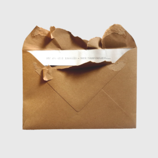 Ein brauner Umschlag, dessen Oberseite aufgerissen ist und der eine maschinengeschriebene Notiz mit teilweise sichtbarem Text im Inneren freigibt.