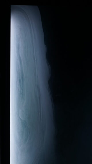 Ein vertikaler Farbverlauf von Hellgrau, der in Dunkelschwarz übergeht, wobei die linke Seite beleuchtet und die rechte Seite größtenteils schwarz ist und an Nebel oder einen Flüssigkeitsstrom erinnert.