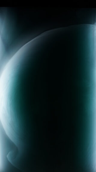 Ein dunkles, abstraktes Bild mit einer großen, sanft leuchtenden, bläulich-grünen, geschwungenen Form vor einem überwiegend schwarzen Hintergrund.