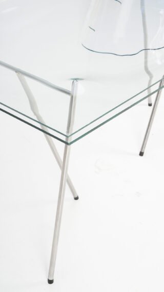 Auf weißem Hintergrund ist ein Glastisch mit durchsichtiger Platte und Metallbeinen zu sehen.