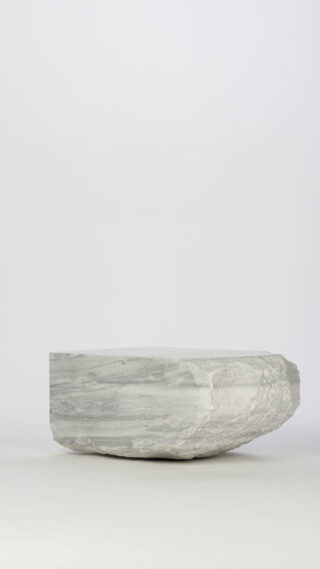 Eine große, flache, graue Steinplatte mit rauen Kanten liegt auf einem schlichten, hellen Hintergrund.