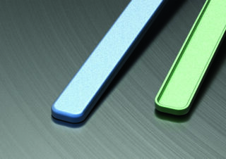 Zwei rechteckige Objekte, eines blau und eines grün, sind diagonal auf einer dunklen, gebürsteten Metalloberfläche platziert.