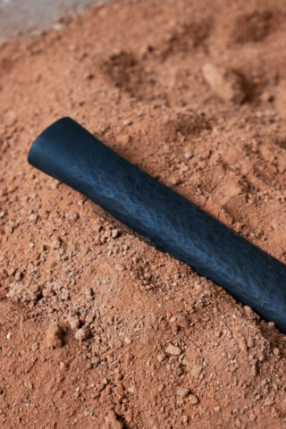 Ein schwarzes zylindrisches Objekt liegt auf einer Oberfläche aus losem, rotbraunem Schmutz.