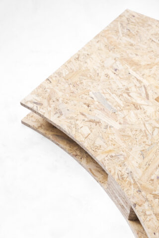 Zwei OSB-Platten (Oriented Strand Board) werden mit ihren abgerundeten Kanten auf einer weißen Oberfläche gestapelt.