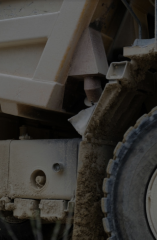 Nahaufnahme des Hinterrads und der schmutzigen Ladefläche eines großen Geländewagens. Man sieht Schlammablagerungen auf dem Reifen und den umliegenden mechanischen Teilen.