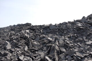 Ein Hügel aus zerklüfteten, dunkelgrauen Schieferfelsen, aufgestapelt im Freien unter einem klaren Himmel.
