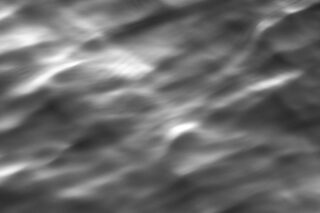 Abstraktes Graustufenbild mit weichen, unscharfen, wellenförmigen Mustern und Farbverläufen, die Lichtreflexionen auf einer Oberfläche oder Wellen im Wasser ähneln.