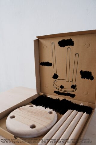 Möbelbausatz zum Zusammenbauen mit Holzteilen und einer Anleitungsabbildung, die so verändert wurde, dass einige Details nicht sichtbar sind, in einem offenen Karton.