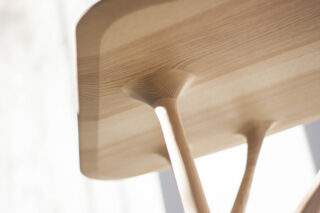 Nahaufnahme der Unterseite eines Holztisches mit glatten, abgerundeten Verbindungen, wo die Beine mit der Tischplatte verbunden sind.