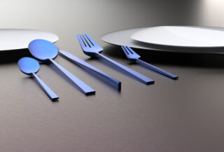 Zwei weiße Teller und fünf blaue Utensilien, darunter zwei Löffel, zwei Gabeln und ein Messer, sind ordentlich auf einer metallischen Oberfläche angeordnet.
