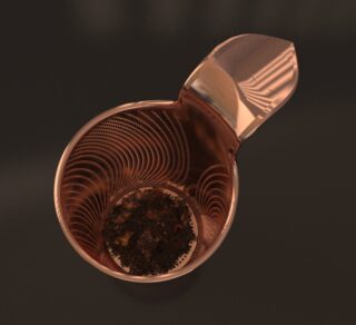 Auf einer dunklen Oberfläche ist ein Tee-Ei aus Metall mit Klappdeckel zu sehen, das losen Tee enthält und geöffnet ist.