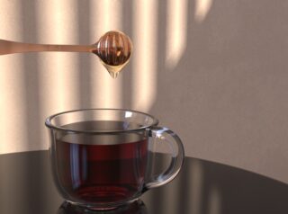 Ein Honiglöffel tropft Honig in eine klare Glastasse mit dunklem Tee, die auf einer reflektierenden schwarzen Oberfläche steht, hinter der sich gestreiftes Licht an der Wand befindet.