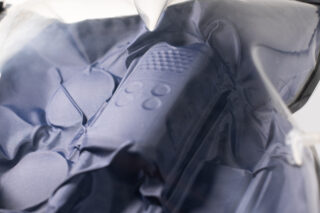 Nahaufnahme einer aufblasbaren Oberfläche mit blauer Textur und erhabenen Kreis- und Gittermustern, die teilweise mit einem transparenten Material bedeckt ist.