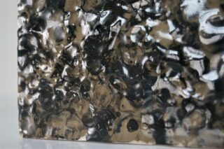 Eine Nahaufnahme einer strukturierten, glänzenden schwarz-beigen Oberfläche mit einem unregelmäßigen, holprigen Muster.