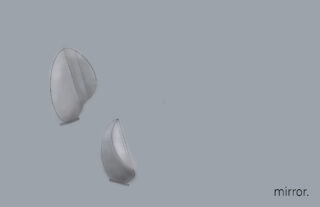 An einer hellgrauen Wand sind zwei abstrakte, ovale Spiegel angebracht. In der unteren rechten Ecke steht in Kleinbuchstaben das Wort „Spiegel“.