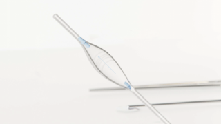 Eine Nahaufnahme eines medizinischen Ballonkatheters mit teilweise aufgeblasenem Ballon und blauen Markierungen vor weißem Hintergrund.