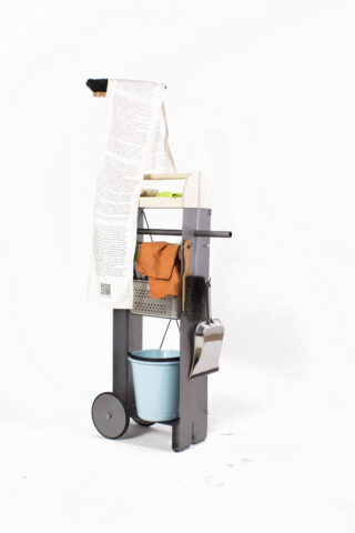 Ein Reinigungswagen mit einem Mopp, Reinigungstüchern, einer Kehrschaufel, einer Bürste und einem blauen Eimer, über dessen Griff vor einem weißen Hintergrund ein langes bedrucktes Papier hängt.