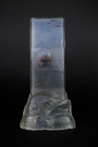 Eine klare, rechteckige Glas-Skulptur mit rauen, unebenen Kanten und einer wolkigen, strukturierten Basis vor einem schwarzen Hintergrund.