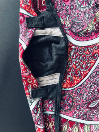 Eine Nahaufnahme der Innentasche aus buntem Stoff mit Paisleymuster mit schwarzem Futter und zwei parallelen weißen Streifen.