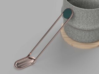 Ein Metallgerät mit flachem Ende und rundem, blaugrünem Griff liegt am Rand eines grauen Steinbehälters auf einer Holzoberfläche.