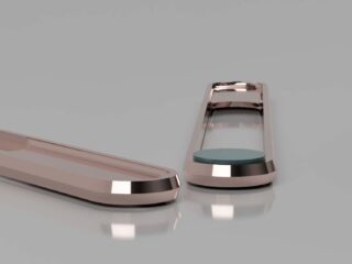 Zwei glatte, metallische Objekte mit reflektierenden Oberflächen werden auf einer glänzenden, hellgrauen Oberfläche platziert; ein Objekt enthält ein kreisförmiges grünes Element.