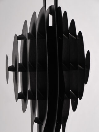 Ein geometrisches, schwarzes Skulpturenobjekt mit sich kreuzenden vertikalen und horizontalen ovalen Scheiben, die symmetrische Schatten auf einen weißen Hintergrund werfen.