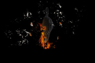 Ein dunkler Hintergrund mit einer transparenten Zielscheibe, umgeben von zersplitterten Fragmenten und orangefarbenen Flammen an der Basis.