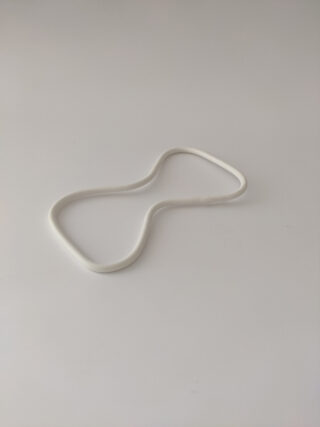 Ein weißes, sanduhrförmiges Plastikobjekt wird auf eine schlichte, helle Oberfläche gelegt.