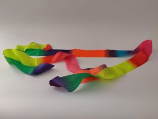 Auf einem schlichten, hellen Hintergrund liegt ein langes, gewelltes Band mit einem Farbverlauf aus leuchtenden Regenbogenfarben.