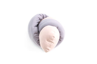 Ein weiches, gedrehtes Kissen in hellen Grau- und Beigetönen liegt auf einem schlichten weißen Hintergrund.